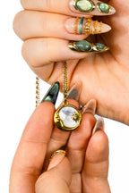 Pendentif collier spirituel Lune or nacre tenu dans des mains de femmes avec ongles 